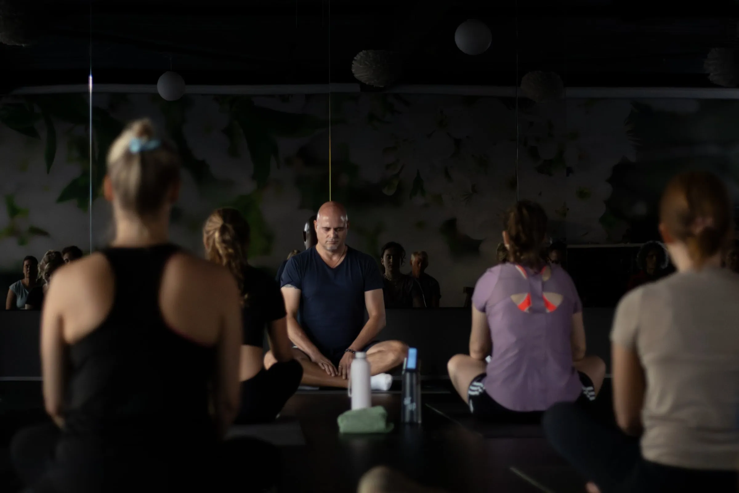 Docent zit met gesloten ogen voor een groep in de zaal