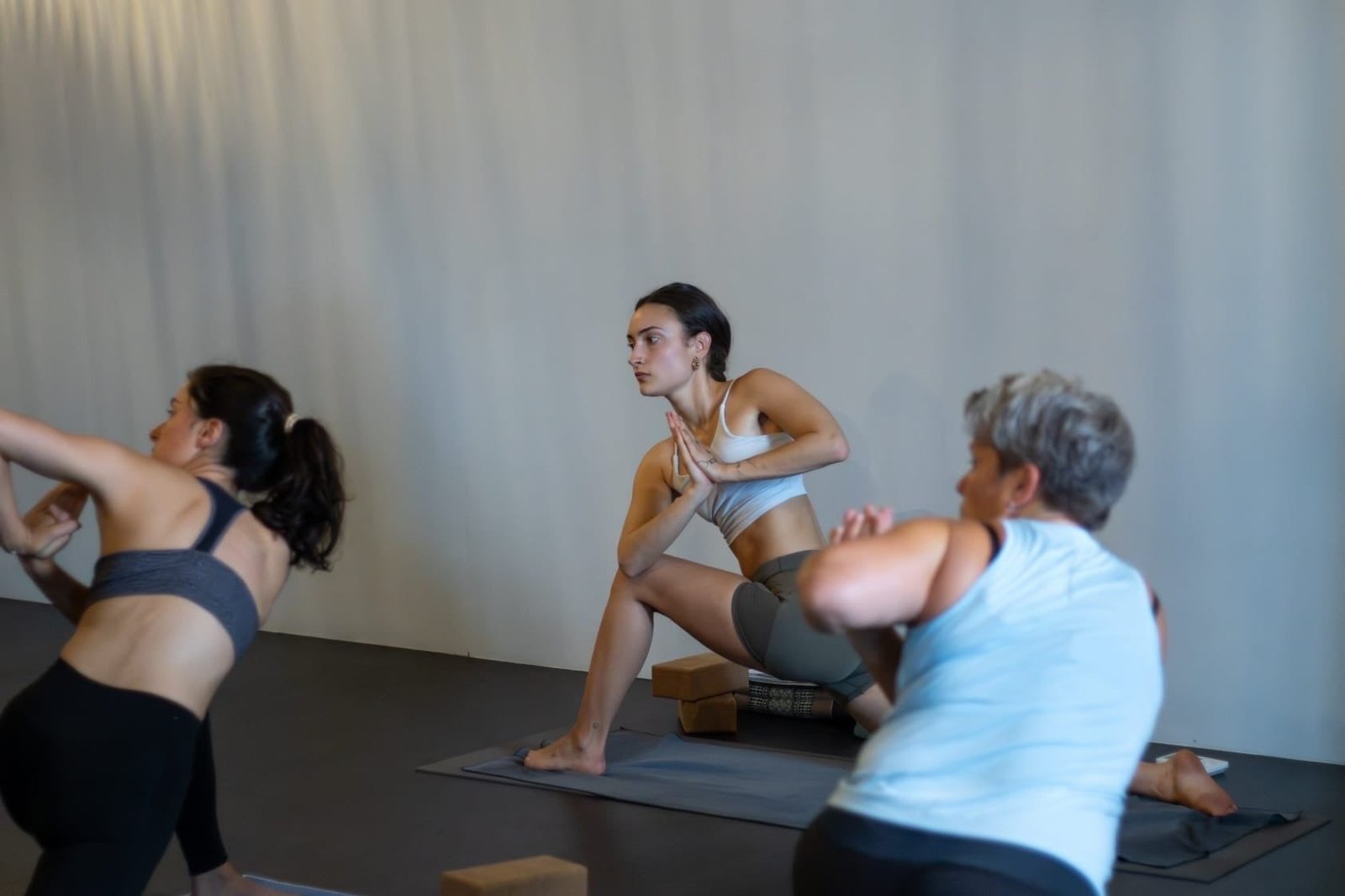 Drie deelnemers in een draaiing tijdens een les in de lichte zaal van Spirit of Yoga