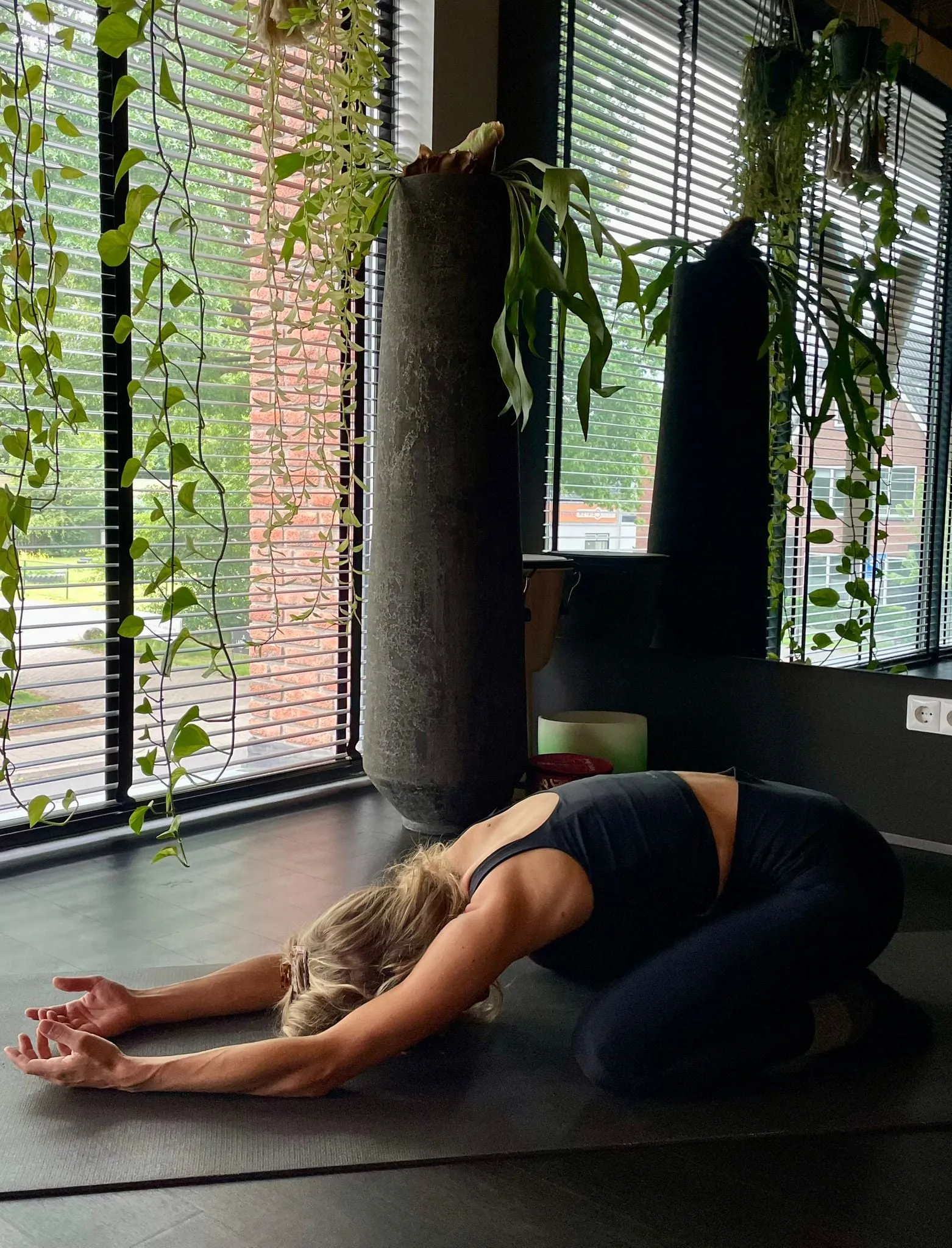 Vrouw in kindhouding op de mat bij het raam met planten