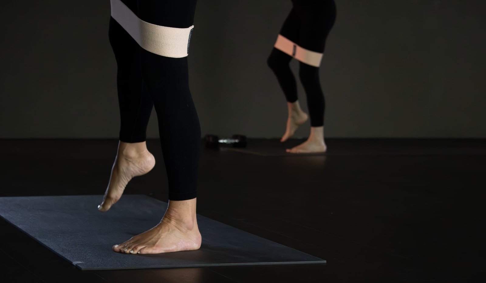 Benen met een weerstandsband op de mat tijdens een pilatesles